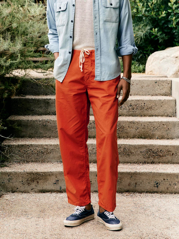 Person wearing bright orange pants and a light blue shirt standing on stone steps outdoors.