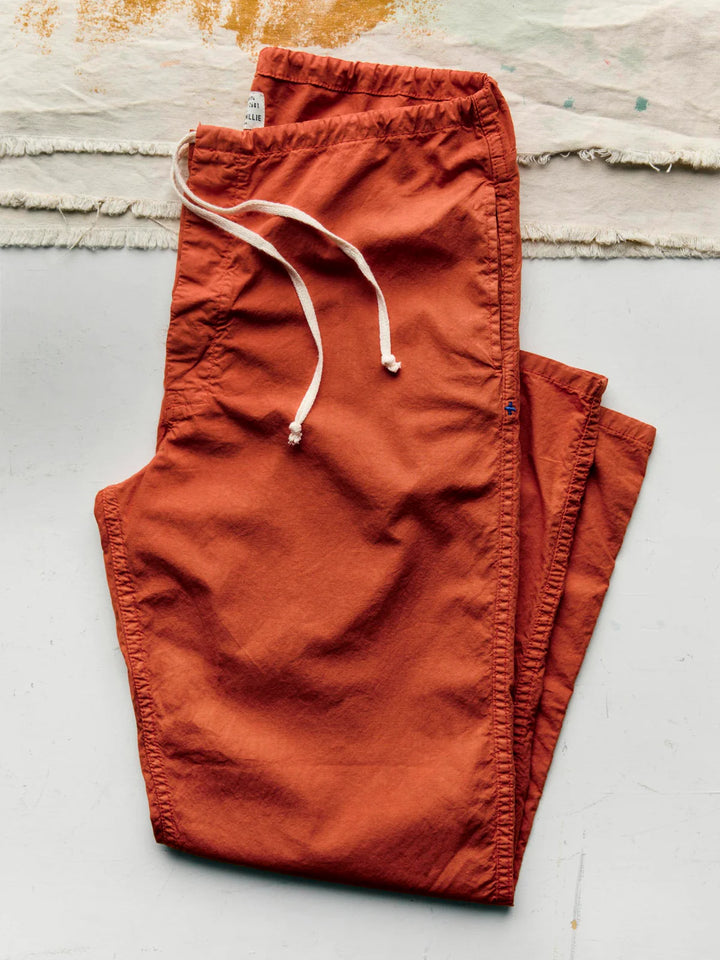 Folded orange pants on a light gray surface with a textured background