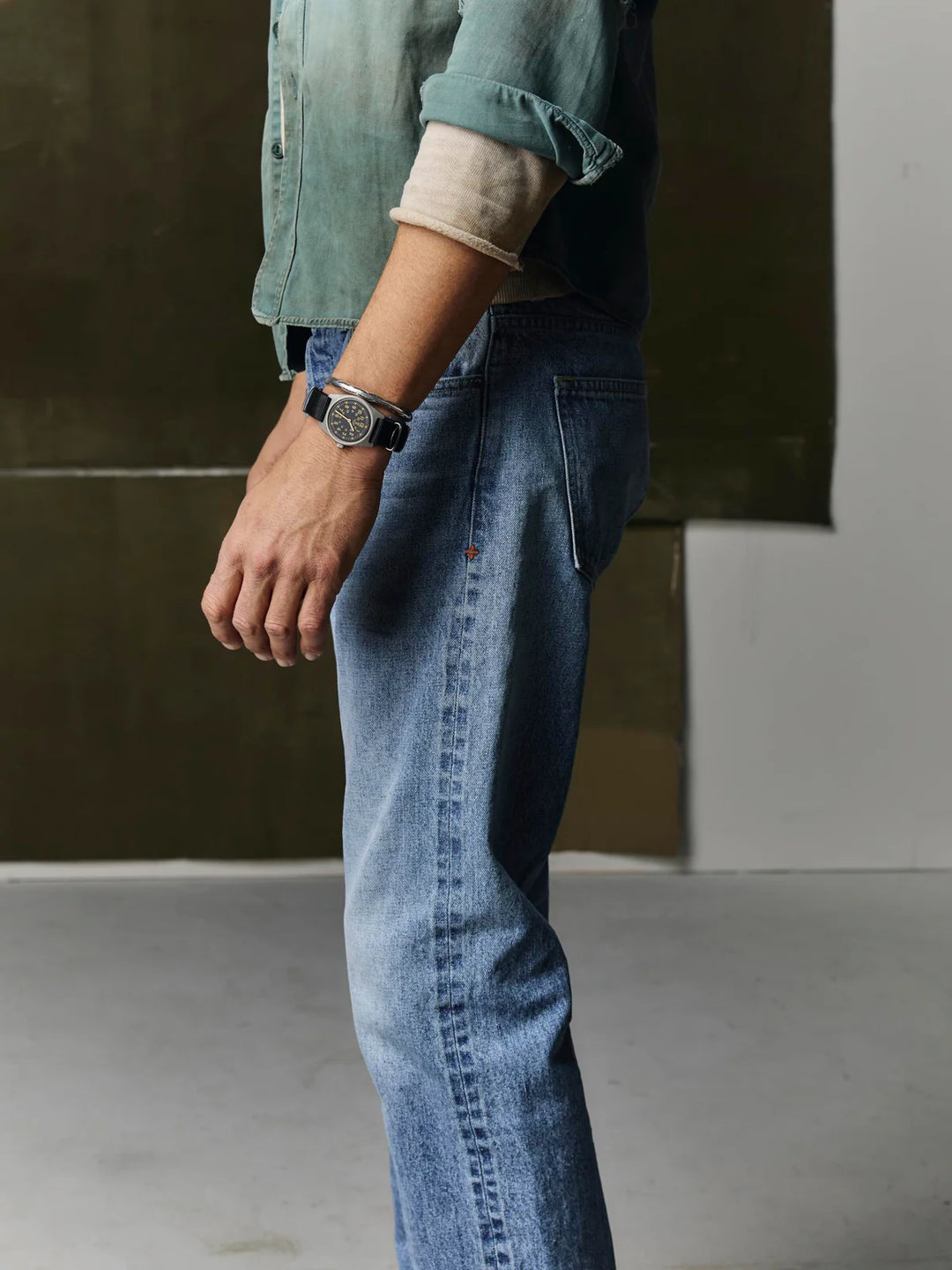Person wearing blue jeans and a green shirt with a blurred background