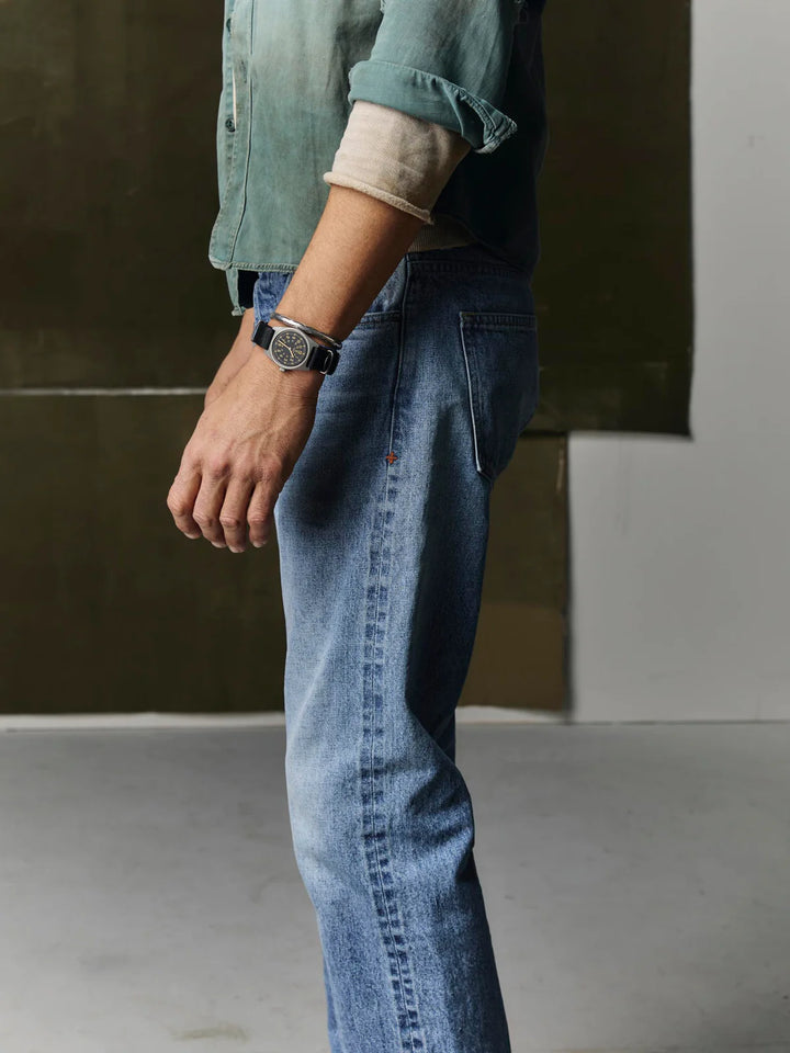 Person wearing blue jeans and a green shirt with a blurred background