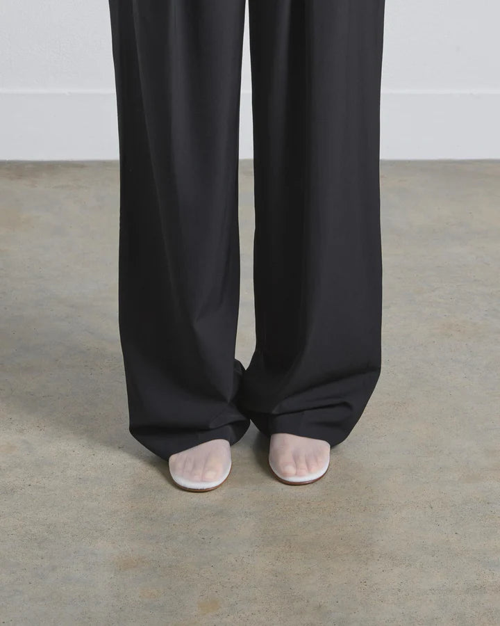 Person wearing black wide-leg pants on a plain background